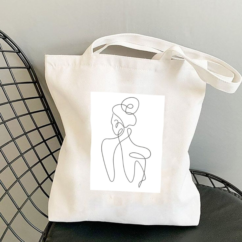 Plátená taška Kiskedves Line Art s postavou zozadu, na čiernej drôtenej stoličke.