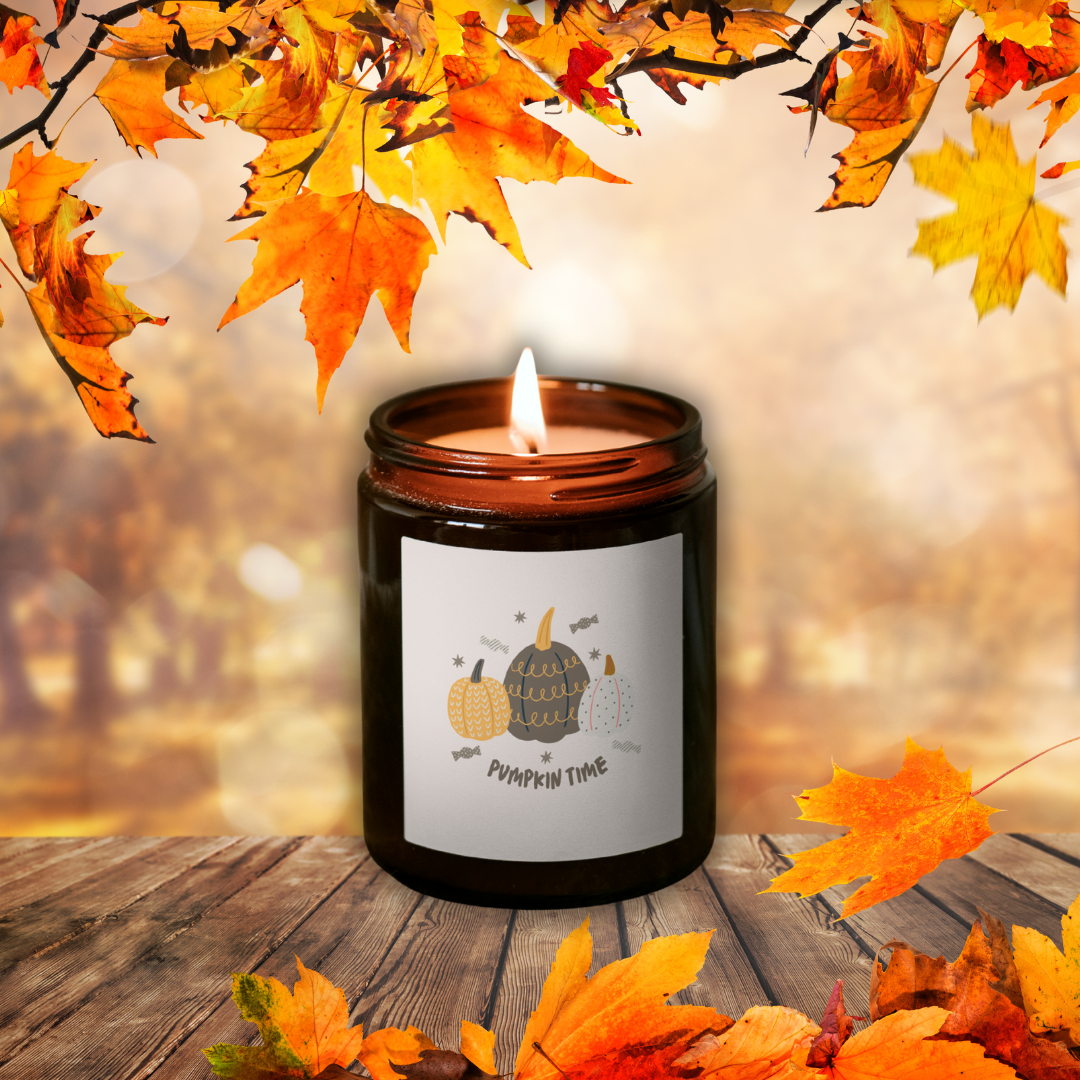 Horiaca sójová sviečka Pumpkin Spice v hnedom pohári so štítkom „Pumpkin time“, medzi jesenným lístím na drevenom stole