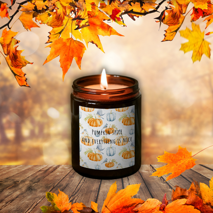 Horiaca sójová sviečka Pumpkin Spice v hnedom pohári so štítkom „Pumpkin spice and everything is nice“, medzi jesenným lístím na drevenom stole