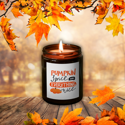 Horiaca sójová sviečka Pumpkin Spice v hnedom pohári so štítkom „Pumpkin Spice and everything nice“, medzi jesenným lístím na drevenom stole