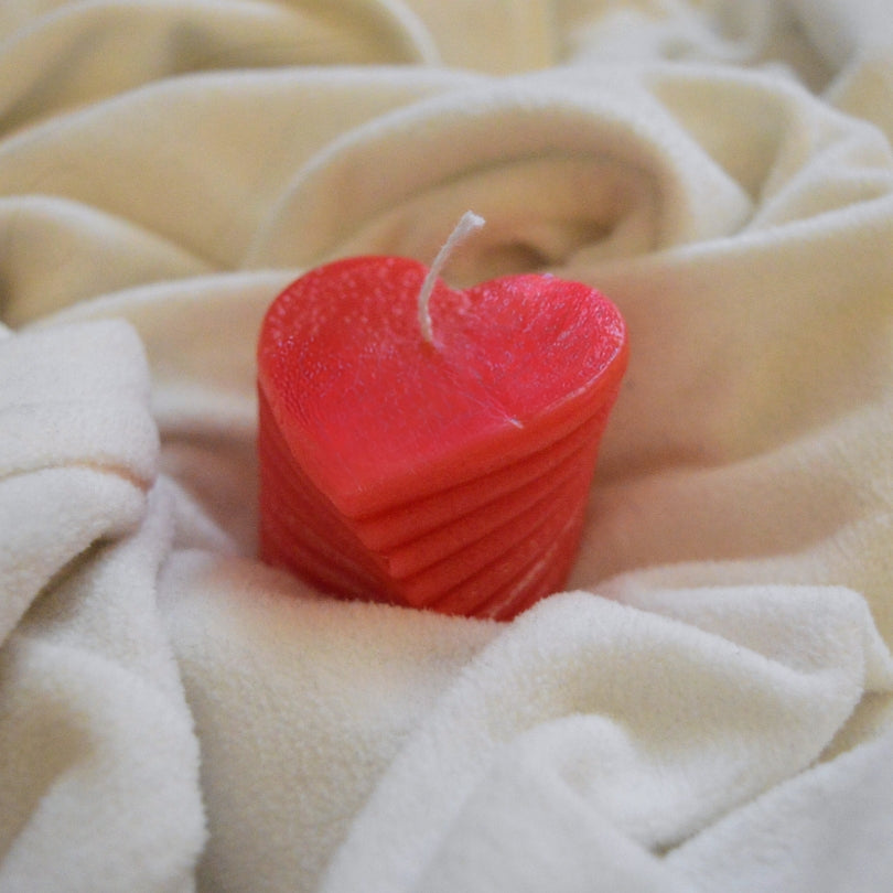Sviečka Sweetheart Kiskedves: červená tvarová sviečka v tvare srdca na krémovej mäkkej deke.
