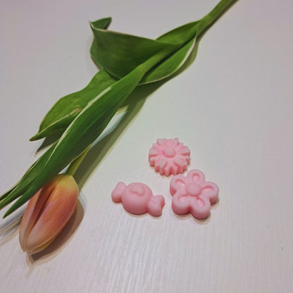 Jarná sada vonných voskov Kiskedves: ružový zajačik, margaréta a kvet na bielom drevenom stole, vedľa tulipán.