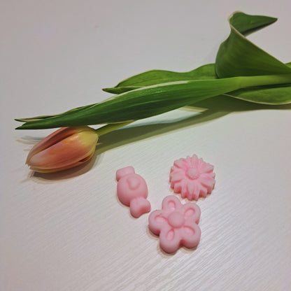 Tri ružové vonné vosky Kiskedves – zajačik, margaréta a kvet – vedľa tulipánu, na bielom drevenom povrchu.