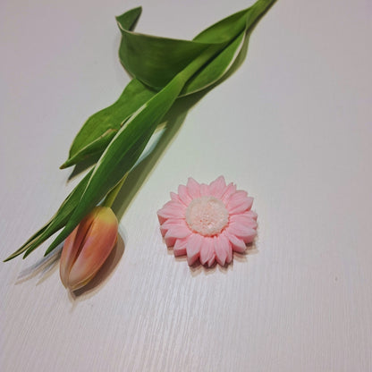 Vonný vosk Kiskedves v tvare kvetu zo sójového vosku, s tulipánom v pozadí, na bielom drevenom povrchu.