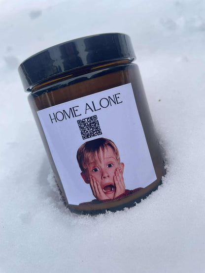 Vianočná sviečka „Melodická“ Kiskedves v snehu, na štítku QR kód a nápis Home Alone